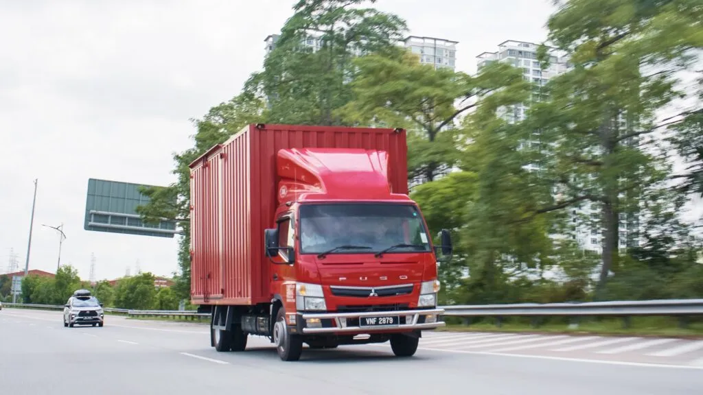 A red Fuso TF Canter box truck travelling on a Malaysian highway during its Johor Bahru to Kuala Lumpur fuel efficiency test drive. (Photo: Hap Seng Trucks Distribution)