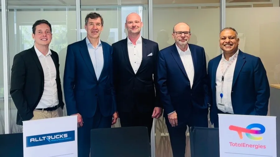 Executives from TotalEnergies Lubrifiants and Alltrucks posing together behind branded table signs during the partnership renewal in Paris. (Photo: TotalEnergies)