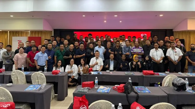 A large group of seminar participants and presenters giving thumbs-up gestures while seated and standing inside a conference hall at Penview Hotel in Kuching.